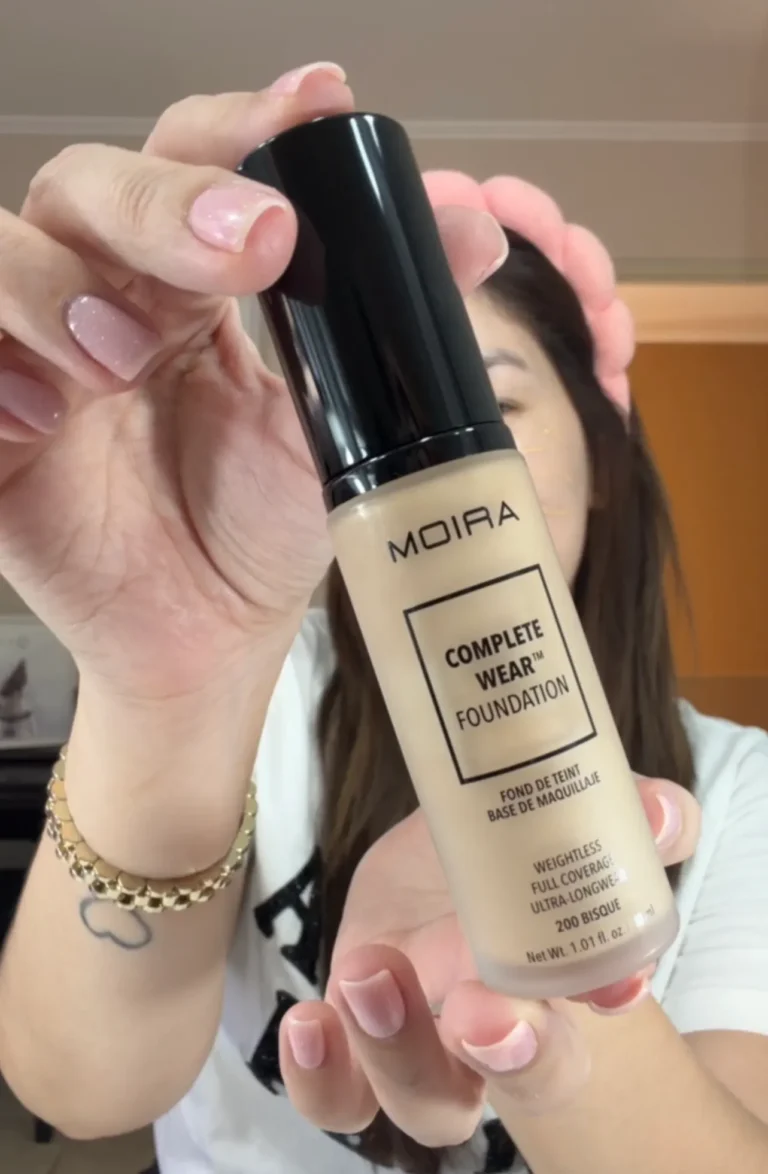 Primer plano de la base de maquillaje Moira Complete Wear Foundation en el tono 200 Bisque sostenida por una mujer.