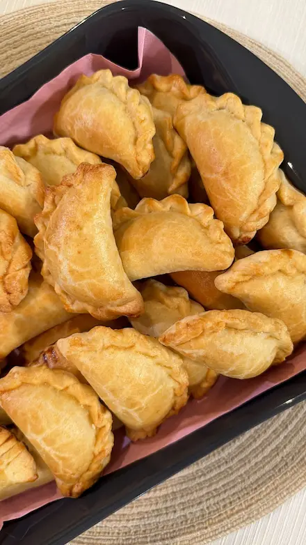 Bandeja llena de empanaditas horneadas y doradas preparadas con la receta de Masa 3-2-1 de Luci Abarca.